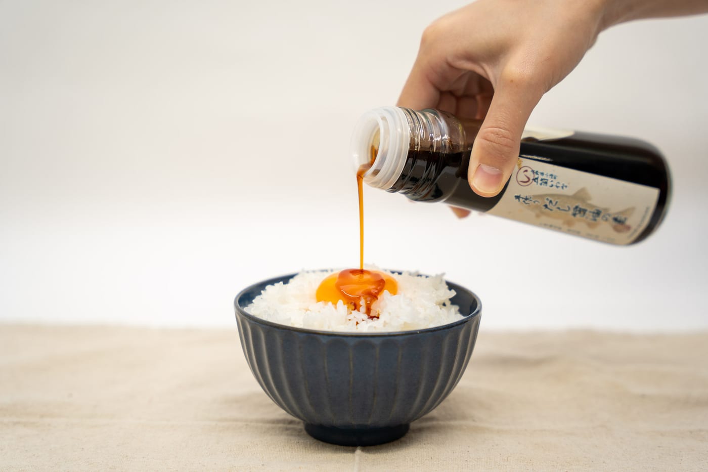 炊きたてのご飯と卵に、いわなのだし醤油をかけているところ